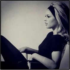 a black and white photo of a woman sitting in a chair with her legs crossed