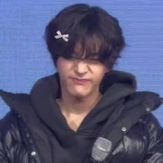 a young man wearing a black jacket and holding a microphone