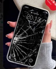 a woman holding an iphone with a cracked screen