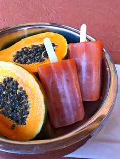 a metal bowl filled with fruit and popsicles