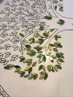 some green leaves are laying on a white table cloth with beadwork in the background