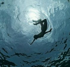 a man is swimming in the water with his feet up and arms out to the side