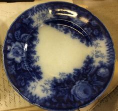 a blue and white plate sitting on top of an old book next to a fork