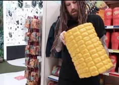 a man with dreadlocks is holding up a giant waffle in a store