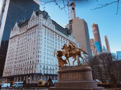 a statue of a man on a horse in front of a building with tall buildings