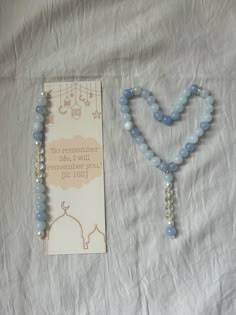 a blue beaded necklace next to a card on a white sheet with an envelope