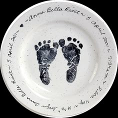 a white plate with two baby footprints on it and the words written in black ink