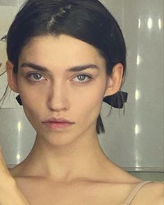 a woman is brushing her hair in front of a mirror and looking at the camera