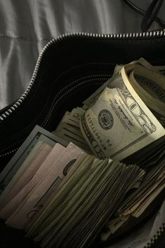 a wallet filled with money sitting on top of a bed