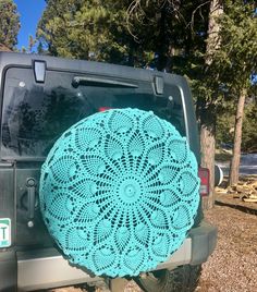 a blue crocheted doily sits on the back of a jeep