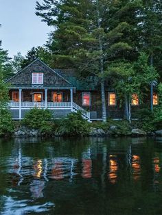a house sitting on top of a lake surrounded by trees