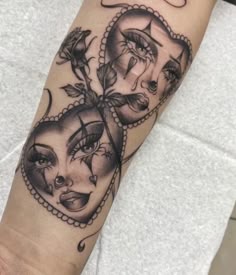 a woman's arm with tattoos on it and two faces in the shape of hearts