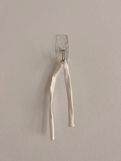a pair of white scissors hanging from a hook on a wall in a room with light colored walls
