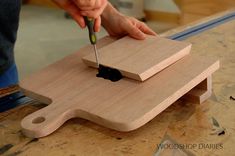 a person using a small knife to cut something on a wooden board with a black object in the middle