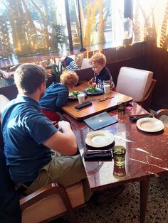 two men and a child sitting at a table with food in front of them on their laptops