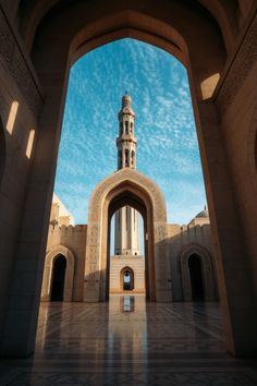 an archway with a clock tower in the middle and blue sky above it, on a sunny day