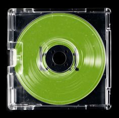 a green plastic disc in a clear case on a black backgrounge background