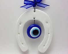 an ornament hanging from a blue ribbon on a white wall with eyeballs