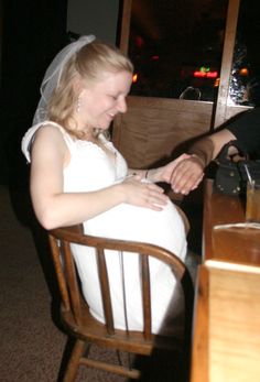 a bride and groom sitting at a table shaking hands
