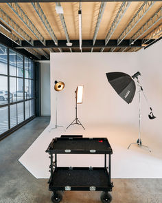 an empty photo studio with lighting equipment in the foreground and lights on the wall