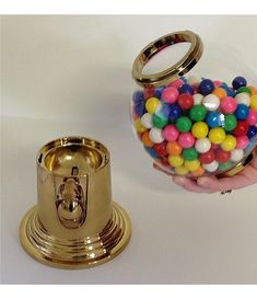 a hand is holding a gold container filled with candy