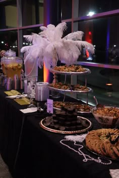a table topped with lots of desserts and pastries next to a tall window