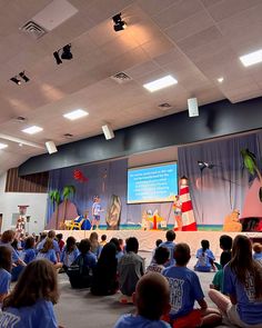 children are sitting on the floor in front of a stage with dr seuss and cat in the hat