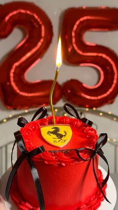 a red birthday cake with a lit candle on top