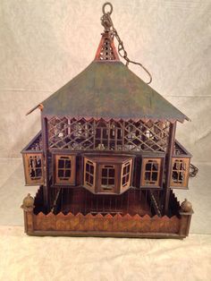 a small wooden house with lots of windows on it's sides and a clock hanging from the roof