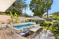 an outdoor patio with table and chairs next to a swimming pool surrounded by greenery