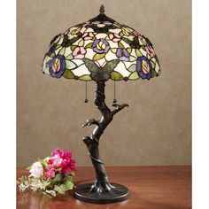 a lamp that is sitting on top of a table next to a vase with flowers