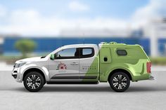 a green and white pick up truck parked on the side of a road next to an ocean