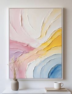 a painting hanging on the wall next to a vase with a plant in front of it