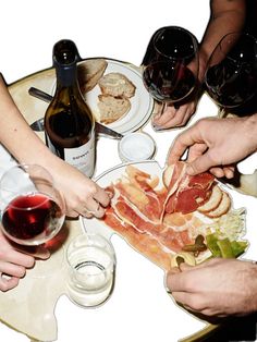 several people are gathered around a table with food and wine glasses on it, all holding their hands together