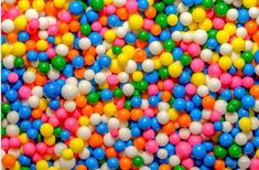 many different colored balls are scattered on top of each other in this image, there is a large amount of them