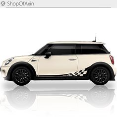 a white mini cooper hatchback car with checkered decals on it's side