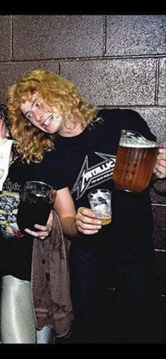 three people standing next to each other holding beer mugs