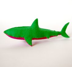 a green toy shark sitting on top of a white table