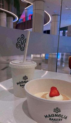 two cups of ice cream with strawberries in them sitting on a table next to each other