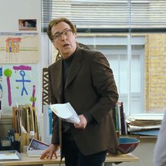 a man standing in front of a desk with papers