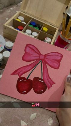 someone is painting a cherry with a pink bow