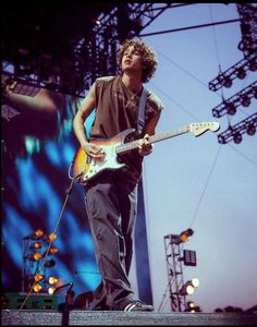 a man standing on top of a stage holding a guitar