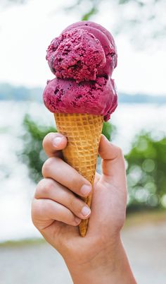 a hand holding an ice cream cone filled with pinkish