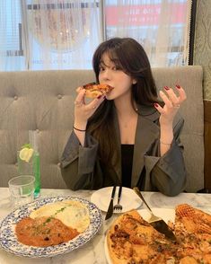 a woman sitting at a table eating pizza