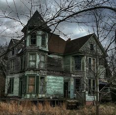 an old, run down house sits in the middle of a field with no leaves on it