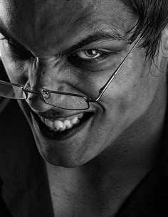 a close up of a person with glasses on his face and mouth, looking at the camera