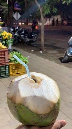 a person holding up a coconut with a straw in it