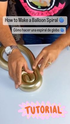 a person is making a balloon ring with their hands while sitting at a table in front of them