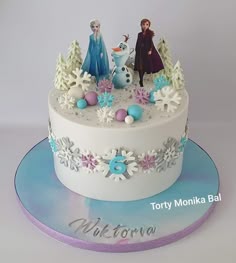 there is a cake with frosting and decorations on the top, including two frozen princess figures