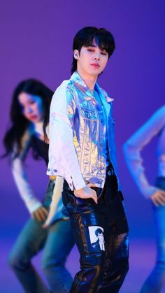 a man standing next to a woman in front of a purple background with other people behind him